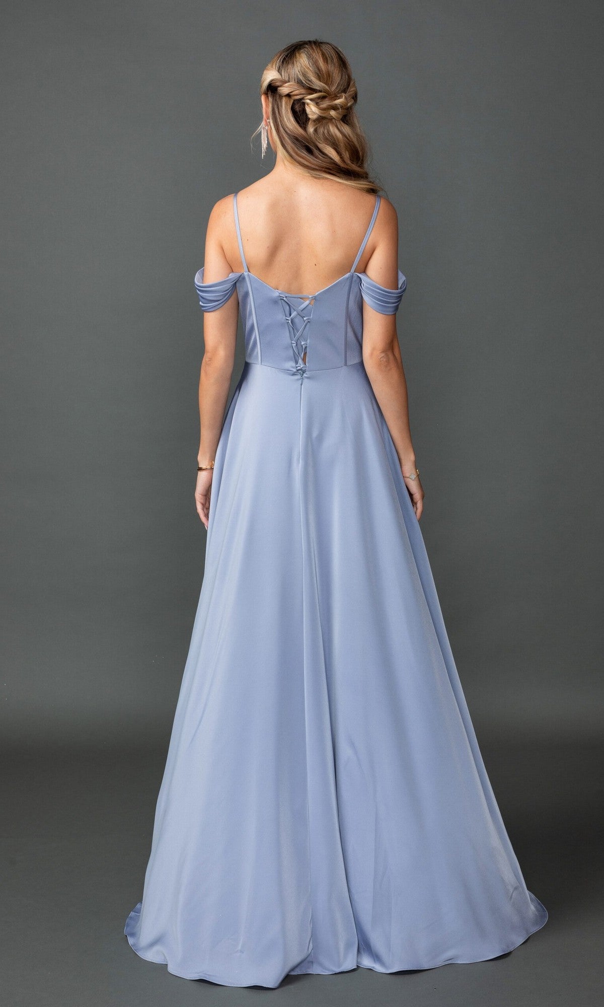 A woman stands with her back to the camera against a plain gray backdrop, wearing the Long Prom Dress: Dancing Queen 4539—a light blue, off-the-shoulder A-line gown featuring a corset bodice and lace-up back.